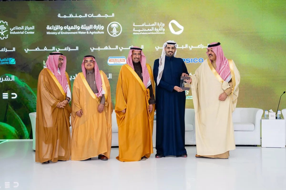 An award is presented on the agri-food forum stage, with the marks of the Industrial Center, the Ministry of Environment, Water & Agriculture and the Ministry of Industry & Mineral Resources on the screen.