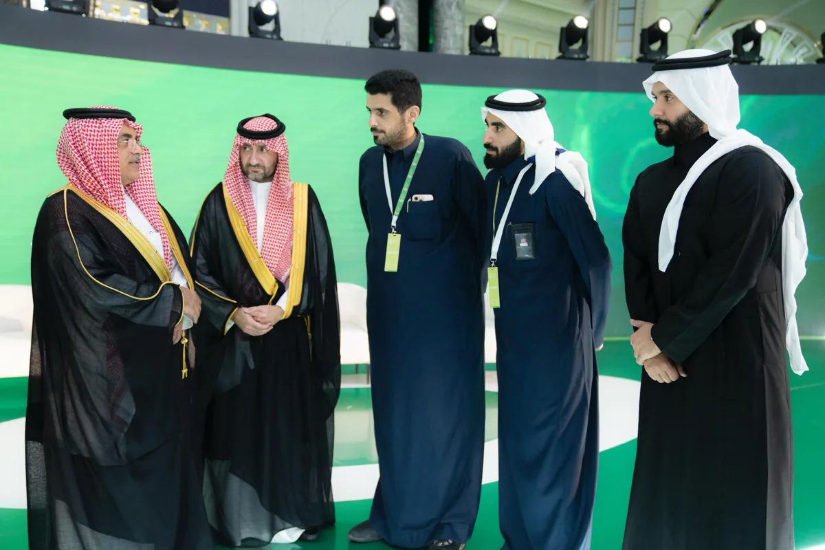 Officials talk on the stage of the agri-food forum for the Ministry of Environment, Water & Agriculture, in front of its green screen.