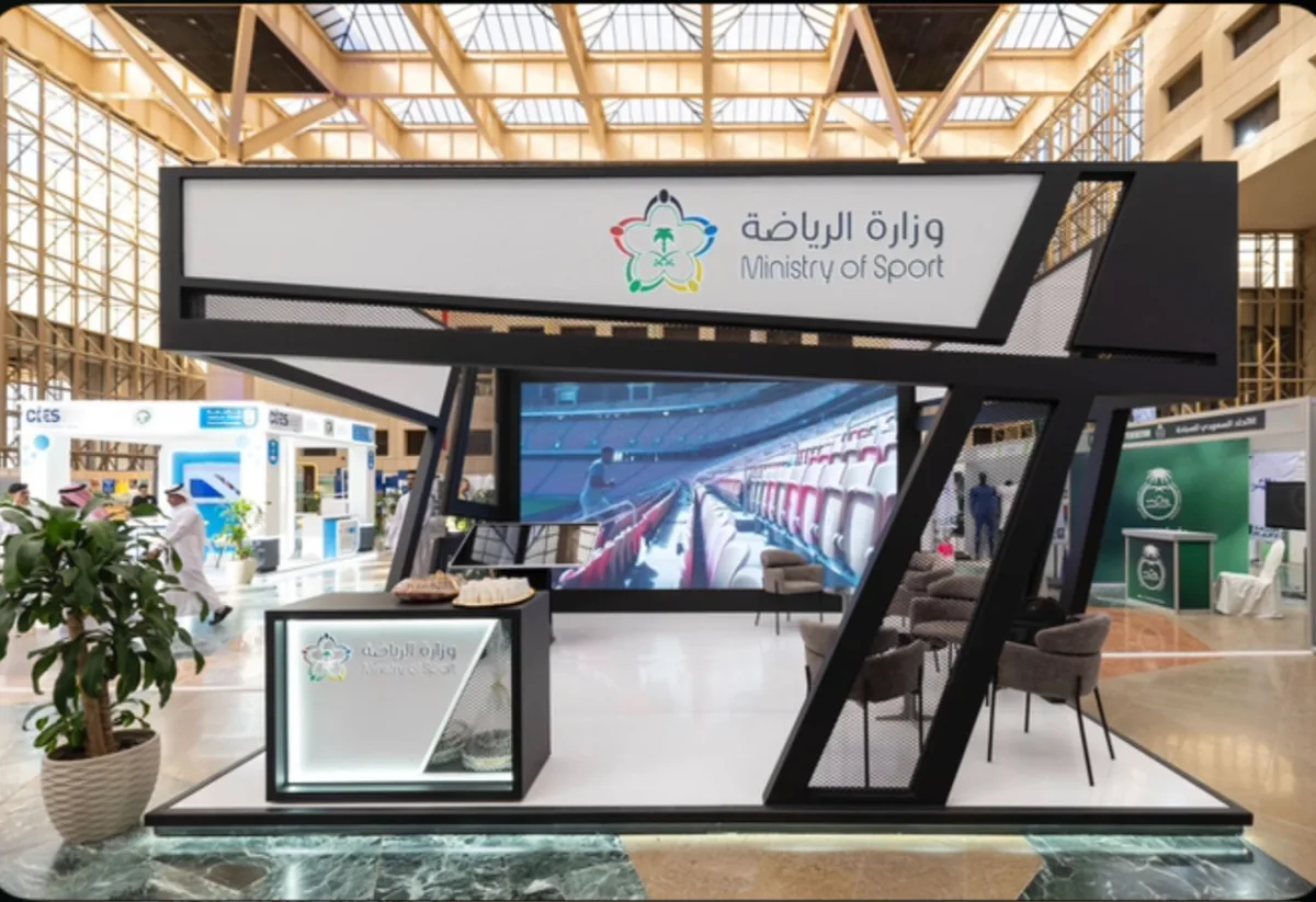 جناح وزارة الرياضة من مستوى واحد تحت مظلّة مرتفعة مائلة، مع جدار شاشات LED.