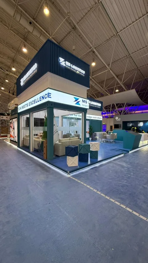 A corner view of the MS Logistics stand, showing the glass-walled lounge inside the container.